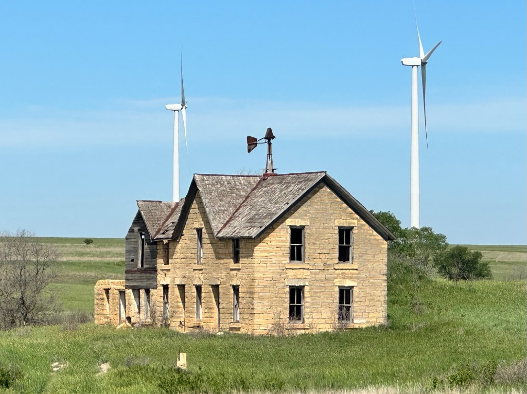 Happy Vegan Campers old limestone house with rusted windmill surrounded by wind turbines in Kansas