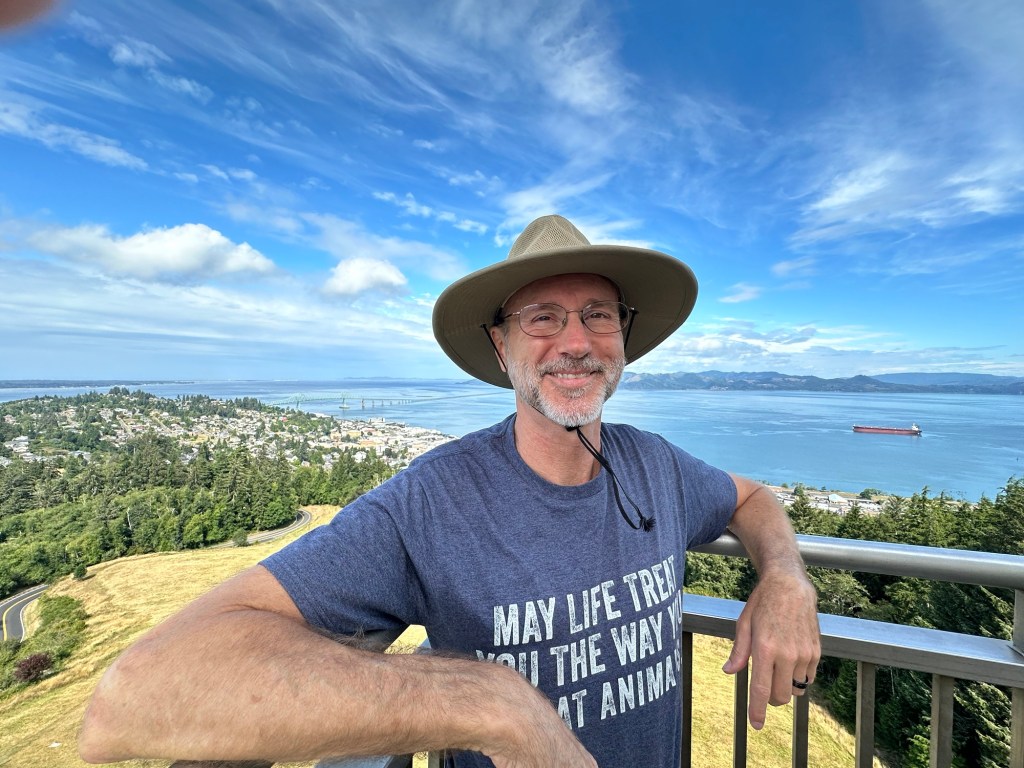 Daniel and the view from Astoria Tower in Astoria, Oregon by Happy Vegan Campers.