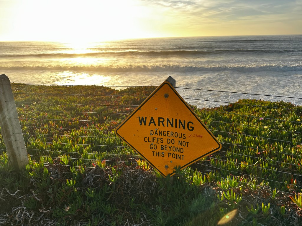 Sign for dangerous cliff in Pacifica, California by Happy Vegan Campers