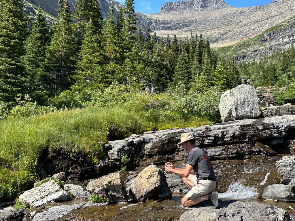 Daniel and waterfall next to Going-To-The-Sun Road in Glacier National Park in Montana, USA. Picture by Happy Vegan Campers.
