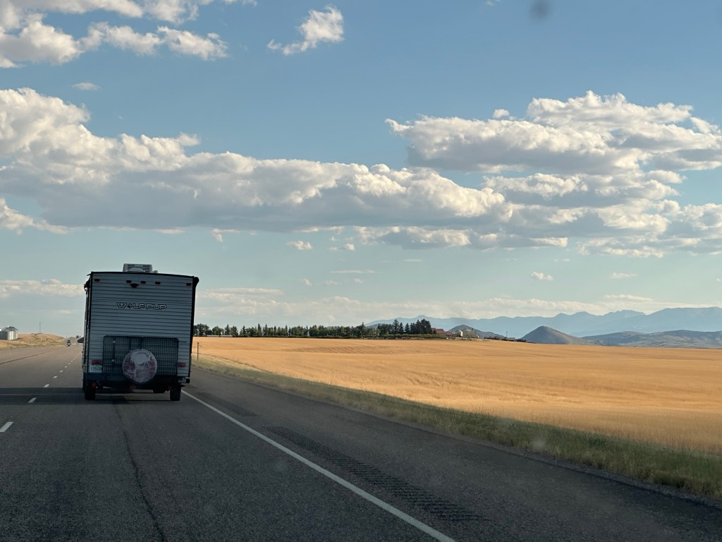 Camper traveling highway next to golden wheat fields in Montana, USA. Picture by Happy Vegan Campers.