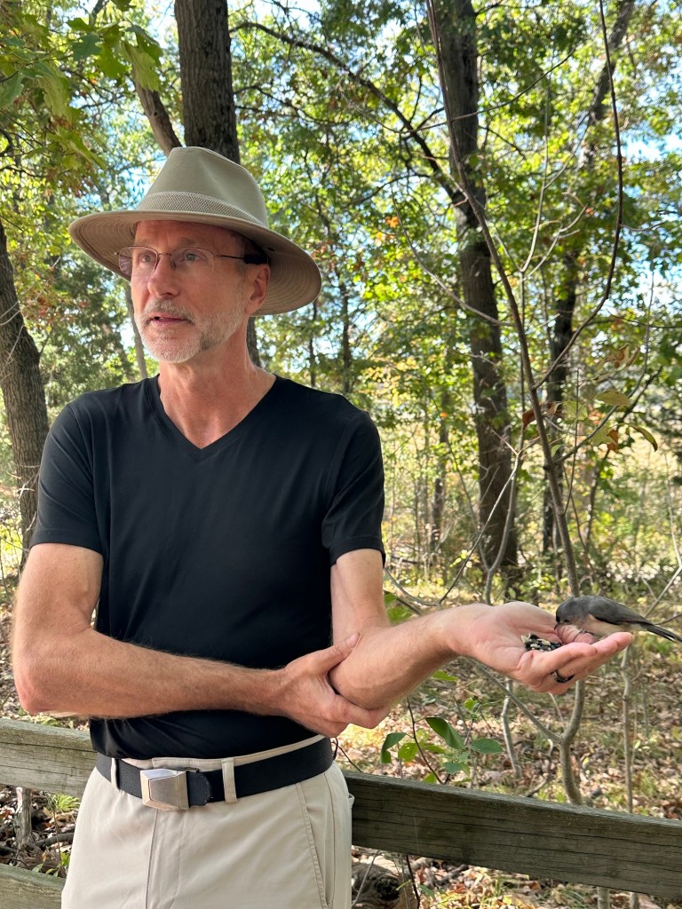 Daniel feeding a bird from his hand in Kensington Metropark, Milford, Michigan, USA.