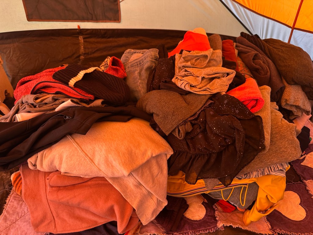 Pile of clothes in tent waiting to be put in storage.
